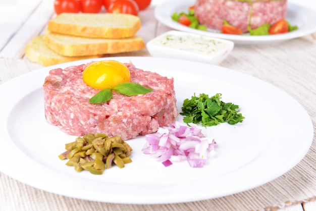 Deliziosa bistecca alla tartara con tuorlo sul piatto sul primo piano del tavolo