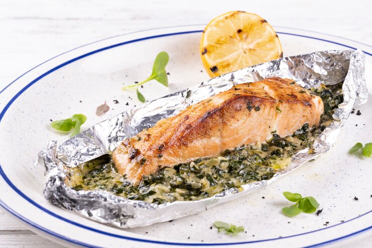Deliziosa bistecca di salmone alla griglia su un piatto bianco su un tavolo di legno bianco