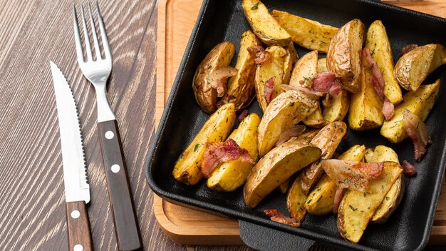 Deliziosa Bratkartoffeln di patate fritte con pancetta e cipolla si chiuda nel piatto nero sul tavolo