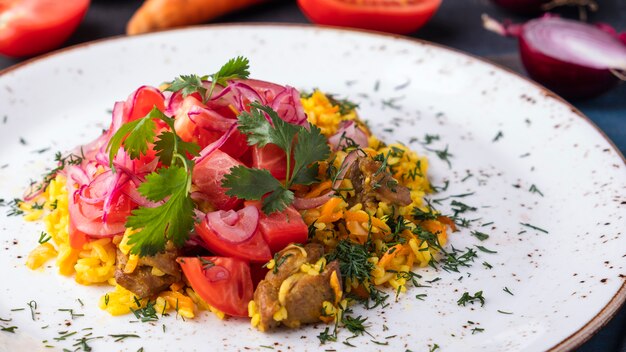 Deliziosa carne pilau, pomodori e cipolle. Cibo uzbeko. Avvicinamento