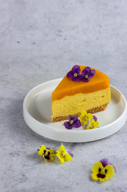 Deliziosa cheesecake al mango con fettine di mango e fiori commestibili