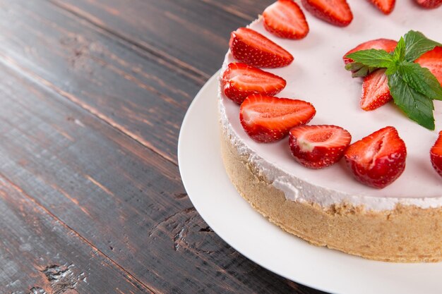 Deliziosa cheesecake con fragole fresche e menta ricetta fatta in casa senza cottura su un tavolo di legno Copia spazio