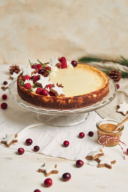 Deliziosa cheesecake natalizia con mirtilli rossi e stelle di biscotti su un tavolo bianco