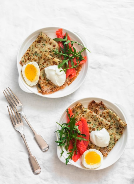 Deliziosa colazione brunch patate crêpes dill uova bollite salmone leggermente arugula su uno sfondo chiaro vista dall'alto