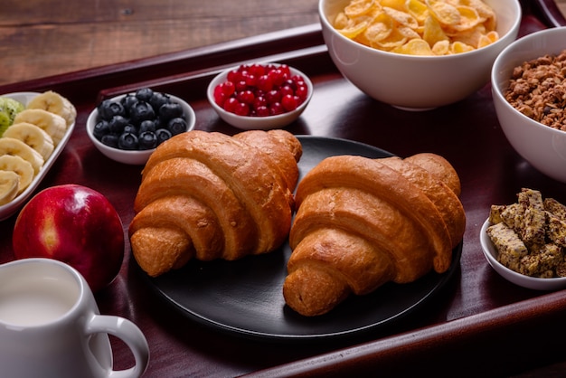 Deliziosa colazione con cornetti freschi e bacche mature su un bellissimo tavolo di legno