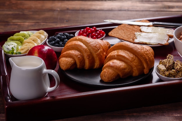 Deliziosa colazione con cornetti freschi e bacche mature su un bellissimo tavolo di legno