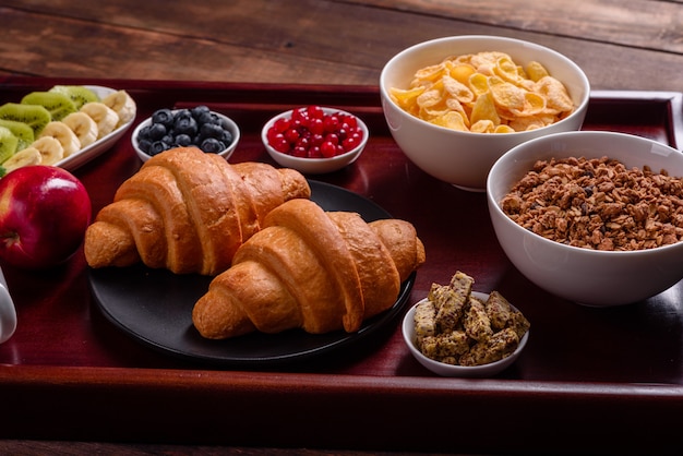 Deliziosa colazione con cornetti freschi e bacche mature su un bellissimo tavolo di legno