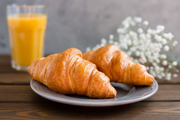 Deliziosa colazione con croissant, fiori e succo di frutta, buongiorno