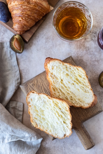 Deliziosa colazione con croissant freschi, marmellata di prugne e succo di frutta su fondo di cemento. Vista dall'alto.