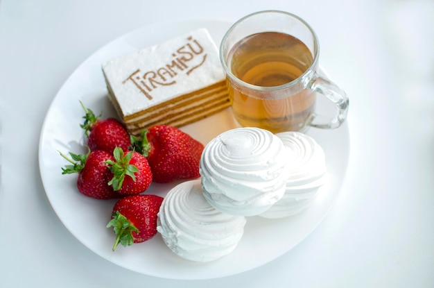 Deliziosa colazione con dessert su un piatto tiramisù fragole marshmallow tazza di tè primo piano