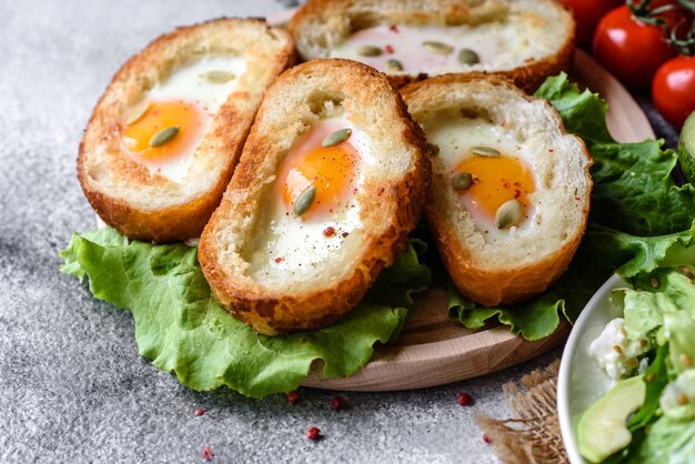 Deliziosa colazione con grugniti, uova, avocado e pomodorini. Piacevole pasto mattutino con panini freschi