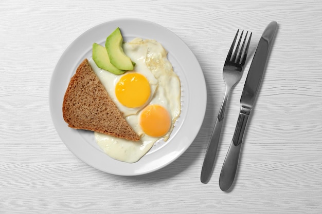 Deliziosa colazione con uova facili su sfondo di legno