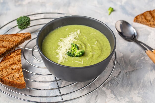 Deliziosa crema di broccoli con parmigiano e crostini di pane croccanti. Zuppa vegana purea di verdure verdi