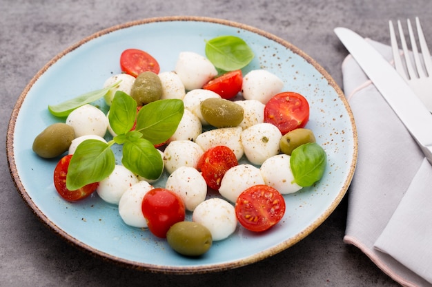 Deliziosa insalata caprese con pomodorini maturi e mini palline di mozzarella con foglie di basilico fresco