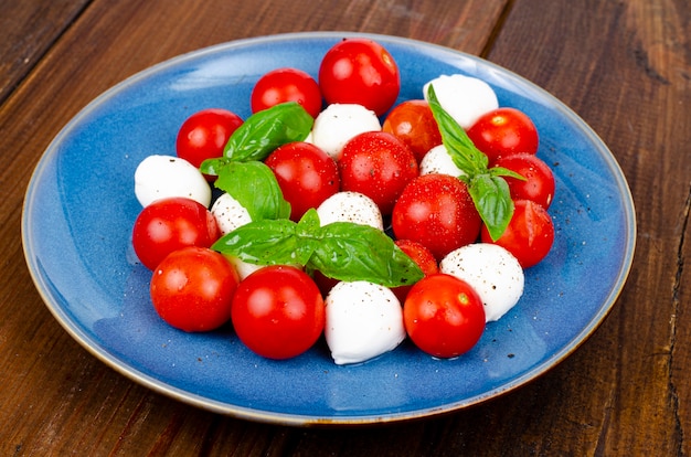 Deliziosa insalata caprese italiana con basilico, mozzarella e pomodorini. Foto dello studio.