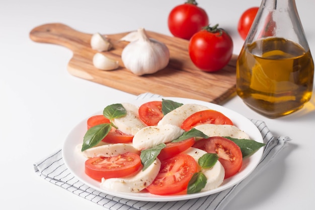 Deliziosa insalata caprese italiana con mozzarella a fette, pesto di basilico e aglio sullo sfondo