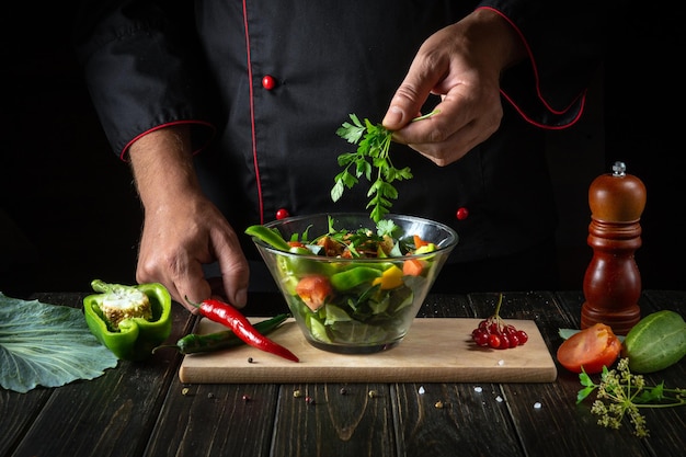 Deliziosa insalata di verdure dalle mani dello chef Il concetto di menu o ricetta per un hotel su sfondo scuro