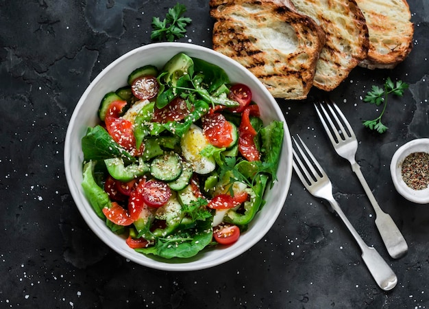 Deliziosa insalata in stile mediterraneo con salmone e uova di lattuga e pane grigliato su uno sfondo scuro vista dall'alto