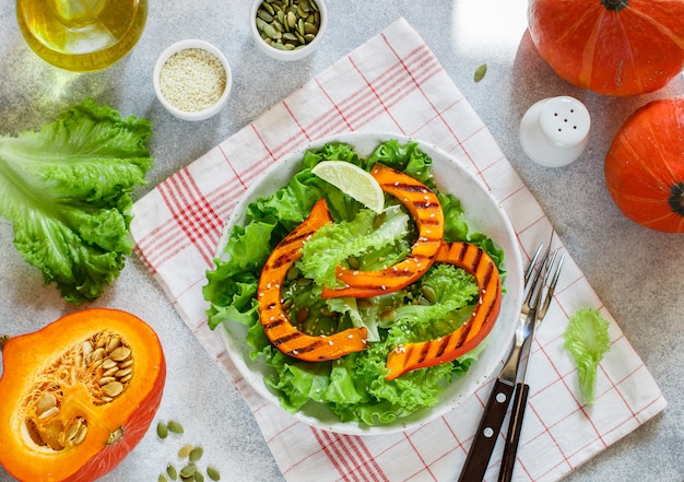 Deliziosa insalata leggera di fette di zucca grigliate e lattuga con semi di sesamo, succo di limone e olio d'oliva