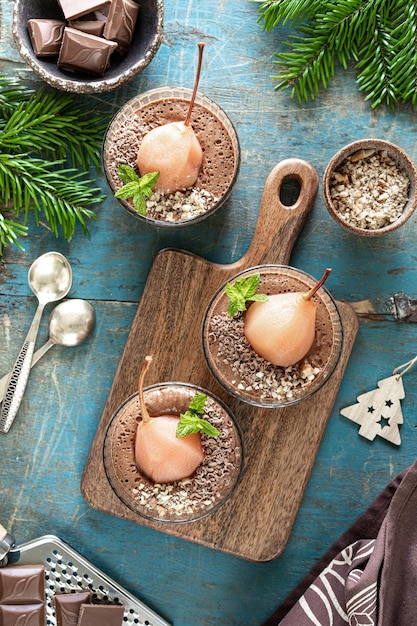 Deliziosa mousse al cioccolato con pere Poach in cornici di vetro su un tavolo di legno blu Verticale