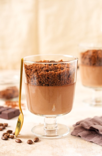 Deliziosa mousse al cioccolato da dessert con brownie in barattoli di vetro su uno sfondo chiaro di ardesia, pietra o cemento. Messa a fuoco selettiva