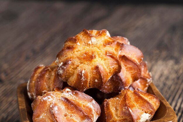 deliziosa pasta choux con zucchero a velo e delizioso ripieno di crema all'interno, torta di pasta e ripieno di latte su un tavolo di legno