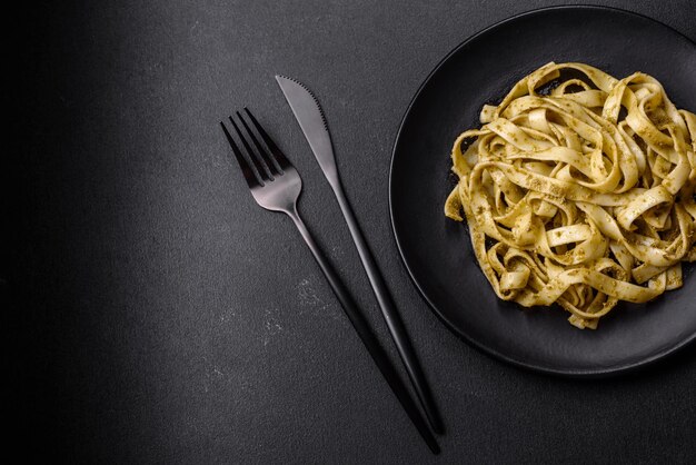 Deliziosa pasta fresca con pesto e frutti di mare su un piatto nero