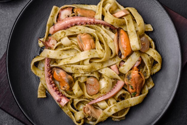 Deliziosa pasta fresca con pesto e frutti di mare su un piatto nero