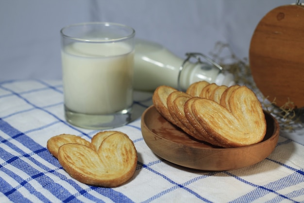 Deliziosa pasticceria su un piatto di legno con un bicchiere di latte