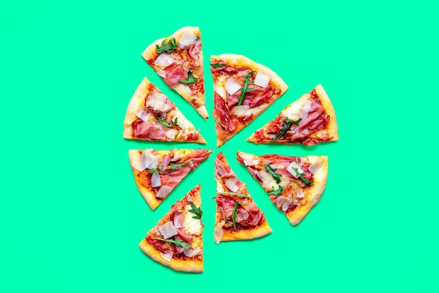 Deliziosa pizza al prosciutto fatta in casa isolata su uno sfondo verde Pizza a fette minimalista su un tavolo colorato