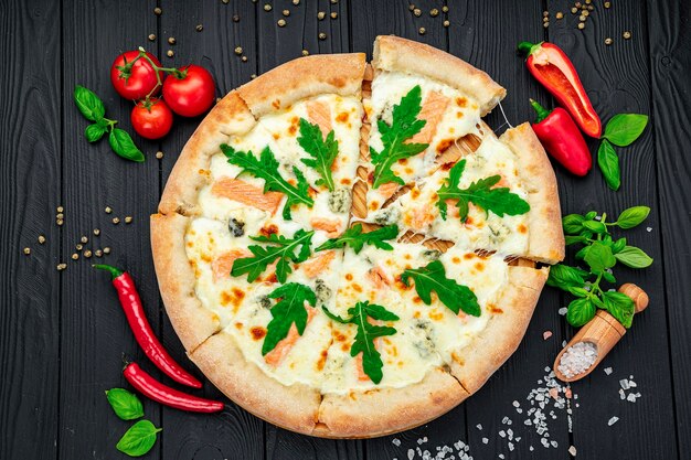 Deliziosa pizza calda con rucola di salmone e diverse spezie sulla tavola di legno pronta da mangiare