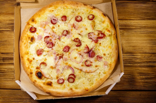 Deliziosa pizza fresca in scatola di cartone su un tavolo di legno Vista dall'alto Concetto per la consegna a domicilio di cibo Fast food consegna della pizza