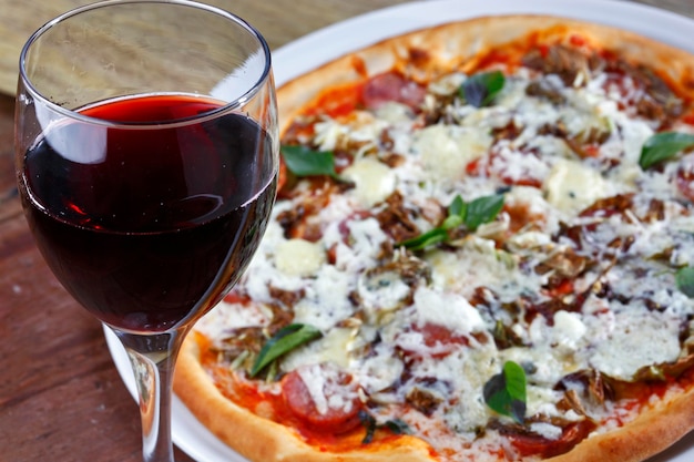 Deliziosa pizza italiana con un bicchiere di vino rosso?