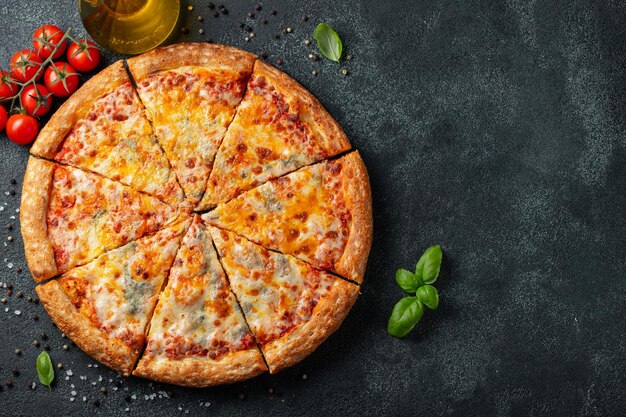 Deliziosa pizza italiana quattro formaggi con pomodori di basilico e olio d'oliva su un tavolo di cemento scuro Vista superiore con spazio di copia Flat lay