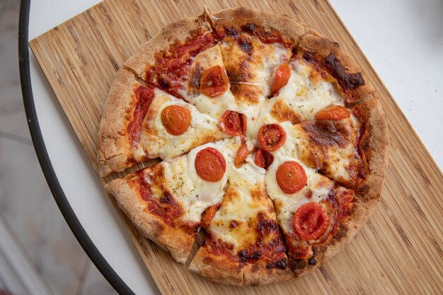 Deliziosa pizza margherita con pomodorini tagliati a fette.