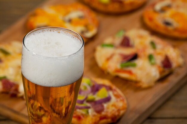 Deliziosa pizza servita su tavola di legno con un bicchiere di birra