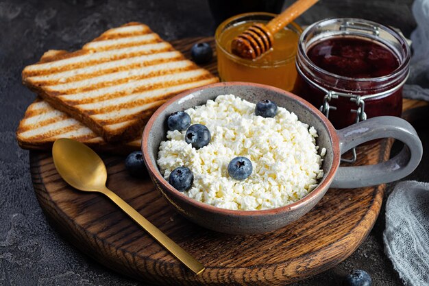 Deliziosa ricotta con mirtillo, miele, marmellata di fragole e pane tostato. Colazione salutare