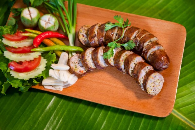 Deliziosa salsiccia di maiale alle erbe alla griglia dal barbecue servita nel ristorante Colpo di primo piano di salsiccia tailandese con contorno di verdure fresche Cibo tailandese