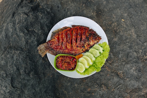 Deliziosa tilapia alla griglia nila bakar dall'indonesia con verdure tempeh di riso e salsa di peperoncino nel piatto