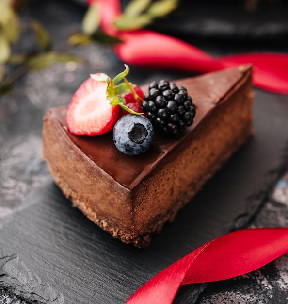 Deliziosa torta al cioccolato decorata con frutti di bosco freschi sul tavolo di pietra