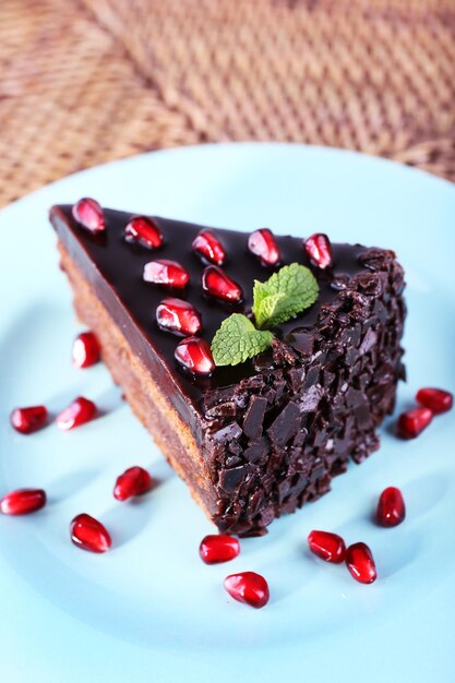 Deliziosa torta al cioccolato decorata con semi di melograno sul piatto sul tavolo