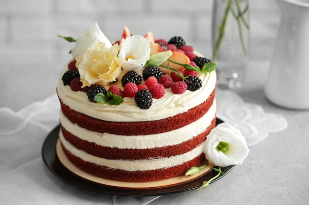 Deliziosa torta con decorazione di frutta e bacche sul tavolo grigio