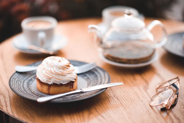 Deliziosa torta cremosa con teiera e tazza di tè sul tavolo di legno