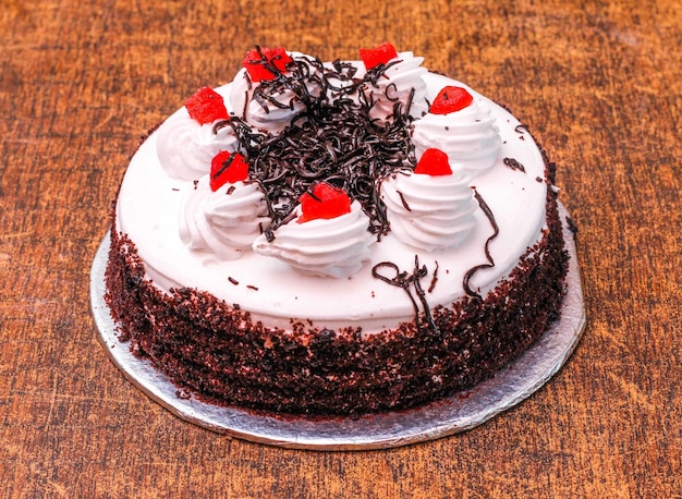 Deliziosa torta della Foresta Nera decorata con panna montata e ciliegie isolate su fondo di legno scuro vista dall'alto