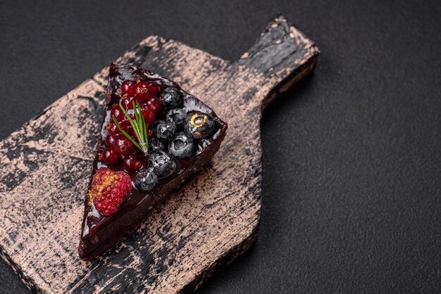 Deliziosa torta di brownie al cioccolato dolce con mirtilli ribes e lamponi su un piatto di ceramica