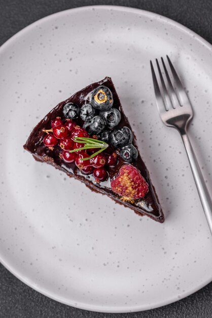 Deliziosa torta di brownie al cioccolato dolce con mirtilli ribes e lamponi su un piatto di ceramica