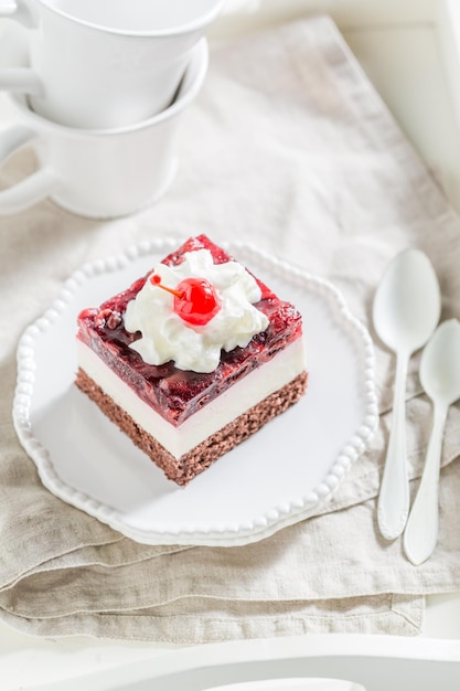 Deliziosa torta di gelatina di ciliegie con crema sul piatto bianco
