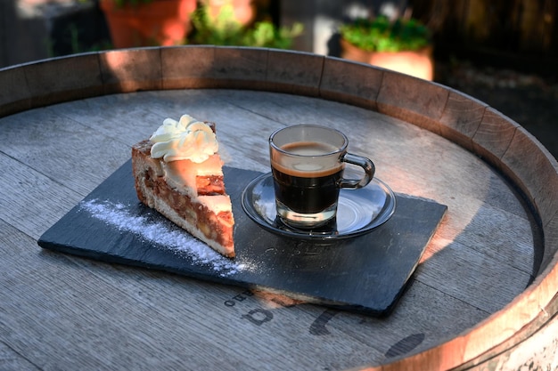 Deliziosa torta di mele con una tazza di caffè espresso servita su una lastra di pietra su un barile di legno