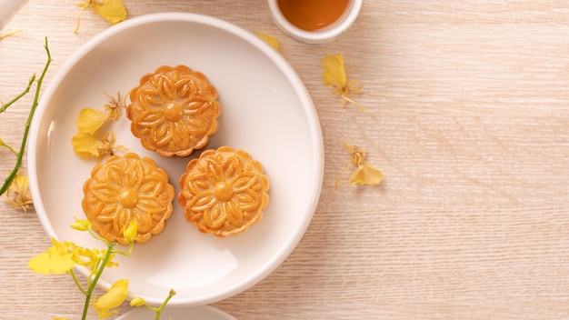 Deliziosa torta lunare per il festival di metà autunno con un bellissimo motivo decorato con fiori gialli e tè Concetto di design festivo di pasticceria pomeridiana