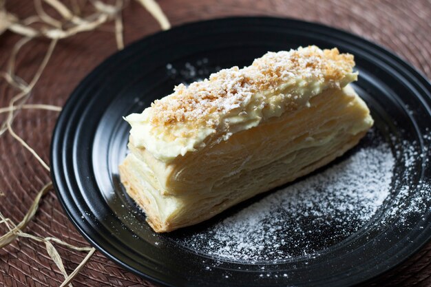 Deliziosa torta napoleone fresca con crema, su un nero.